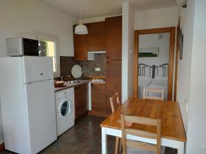a kitchen with a wooden table and a white refrigerator at Apartamentos Corona in Comillas
