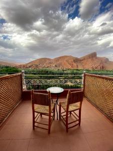 d'une table et de deux chaises sur un balcon avec vue sur les montagnes. dans l'établissement Maison La Vallée Des Figues Dadès, à Tamellalt