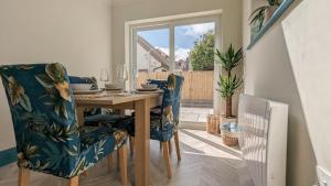 a dining room with a wooden table and blue chairs at The Retreat in Holland-on-Sea