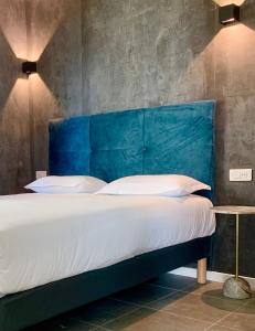 a bed with a blue headboard in a room at Bella Vista Hôtel, Suites & Maisons in Porticcio