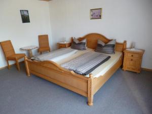 a large wooden bed in a room with two chairs at Ferienwohnungen im Himmelreich in Lam