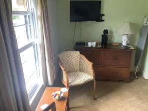 a room with a chair and a dresser and a television at Bwthyn Cudd in Westbury