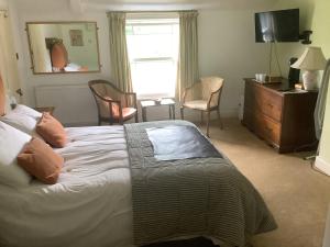 a bedroom with a bed with a dresser and a window at Bwthyn Cudd in Westbury