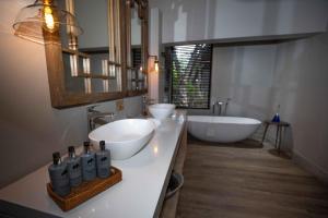 ein Badezimmer mit zwei Waschbecken, einer Badewanne und einem Spiegel in der Unterkunft Elephant Plains Game Lodge in Sabi Sand Game Reserve
