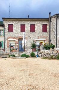 a stone building with red shuttered windows on it at Una Chicca in Valdobbiadene