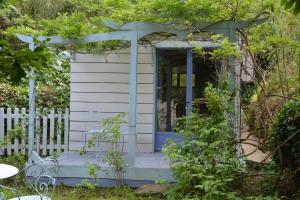 a white shed with a blue door in a garden at Maison d'Hôtes Le Calme in Saint-Tropez