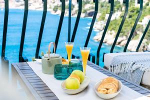 una mesa con comida y dos vasos de zumo de naranja en Beach House Sveti Jakov 2 en Dubrovnik