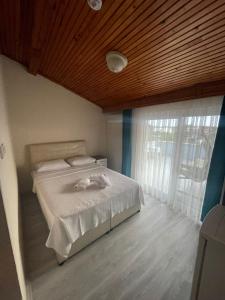 1 dormitorio con cama blanca y techo de madera en Blue Topas Otel, en Burhaniye