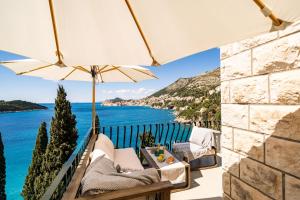 uma vista para o oceano a partir de uma varanda com um guarda-sol em Beach House Sveti Jakov 2 em Dubrovnik