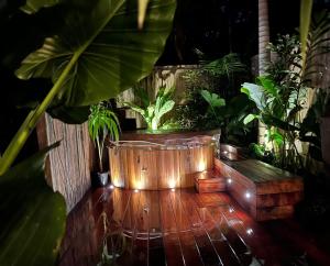 拜倫灣的住宿－Beach Jungle - Hot Tub, Firepit & Pool in Beachside Oasis，木地板,配有种植了植物的大型木制浴缸