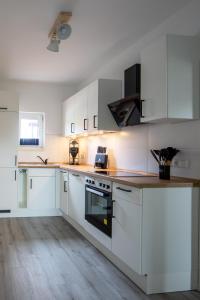 Una cocina blanca con gabinetes blancos y piso de madera. en Ferienhaus Annika in Schillig-Horumersiel mit 8 modernen Wohnungen, en Schillig