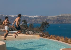 two men jumping off the side of a swimming pool at Divino Caldera in Akrotiri