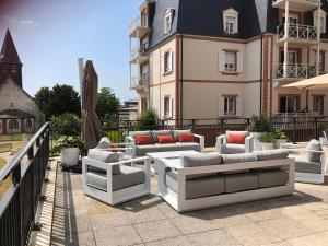 a patio with white couches on a balcony at Villa Médicis Trouville-sur-mer in Trouville-sur-Mer