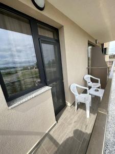 einen Balkon mit zwei weißen Stühlen und einem großen Fenster in der Unterkunft Studios and Apartments Pomorie in Pomorie
