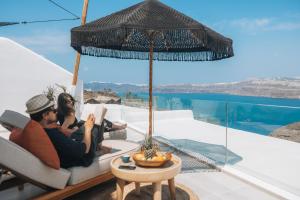 a man and woman sitting in a chair under an umbrella at Divino Caldera in Akrotiri