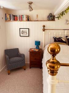 a bedroom with a bed and a chair at Olive's Cabin in Helston