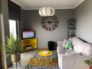 a living room with a couch and a clock on the wall at Piso en la Playa in Ribeira