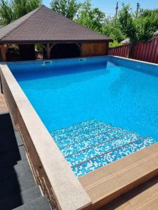 ein Schwimmbecken mit blauem Wasser und ein Pavillon in der Unterkunft Vila Mario in Galaţi