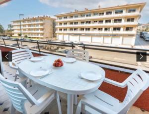 una mesa blanca y sillas en un balcón con un edificio en Apartamento familiar, en Torroella de Montgrí