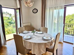 ein Esszimmer mit einem Tisch mit Stühlen und einer Uhr in der Unterkunft Apartments Villa Ida in Opatija