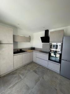 a large kitchen with white cabinets and appliances at La maison du Port Apt ROMA in Marseillan