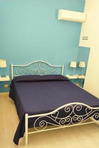 una camera da letto con letto con lenzuola viola e pareti blu di Villa delle Muse a Fontane Bianche