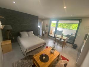 um quarto com uma cama e uma sala de estar com uma mesa em Appartement avec Terrasse couverte - La Motte-Servolex em La Motte-Servolex