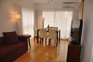 a living room with a table and a couch and a television at Livin' Residence Rosario in Rosario