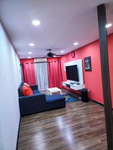 ein Wohnzimmer mit einem blauen Sofa und einer roten Wand in der Unterkunft 3 Bedrooms with Pool Hanan Residence Ketumbar Heights Condominium in Cheras