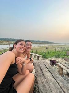 two young women sitting on a wooden bench at Bamby Chilling House in Sauraha