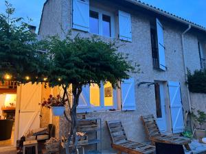 een huis met blauwe ramen en stoelen en een boom bij Maison charmante idéale pour des vacances sur la côte d'Azur in Antibes