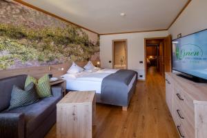 ein Hotelzimmer mit einem Bett und einem Flachbild-TV in der Unterkunft Hotel Grien in St. Ulrich in Gröden