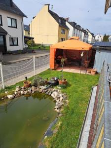 a backyard with an orange tent and a pond at Ferienwohnung Hilgert in Sankt Sebastian