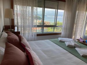 een bed in een slaapkamer met een groot raam bij Casa a 2 minutos andando a la playa de Panxón in Nigrán