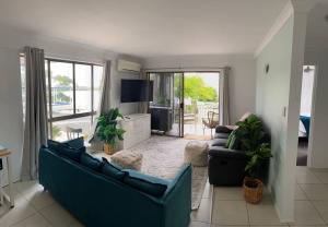 a living room with two blue couches and a television at Callie Beach Escape - Beachside View, Family Friendly, Walk Everywhere in Caloundra