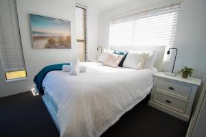 Un dormitorio con una gran cama blanca y una ventana en Callie Beach Escape - Beachside View, Family Friendly, Walk Everywhere en Caloundra