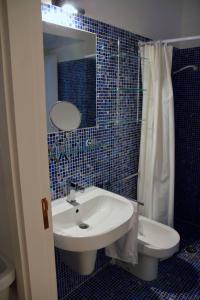 a blue tiled bathroom with a sink and a toilet at Casa Mirabella in Siracusa