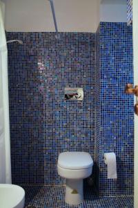 a bathroom with a toilet and a blue tiled wall at Casa Mirabella in Siracusa