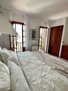 uma grande cama branca num quarto com janelas em Townhouse at the Beach em Estepona