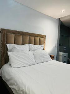 a large bed with white sheets and pillows at Urban Retreat with a View in Windhoek
