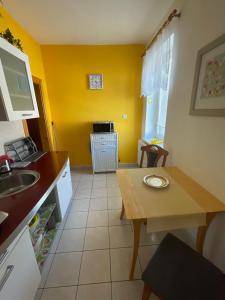 eine Küche mit gelben Wänden, einem Tisch und einem Waschbecken in der Unterkunft Ubytování u Medvěda in Rokytnice v Orlických horách