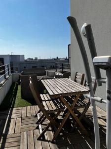 uma mesa de madeira e cadeiras sentadas num deque em Grand T2 La Plaine Saint Denis em Saint-Denis