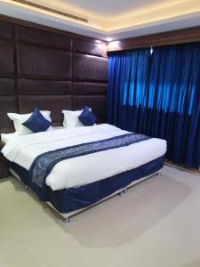 فندق روزلاين في الرياض: غرفة نوم بسرير كبير مع ستائر زرقاء