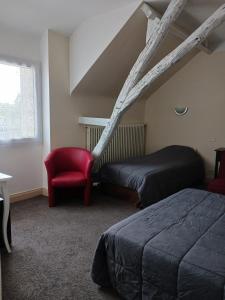 Habitación con 2 camas y silla roja. en Hôtel du Puy d'Alon en Souillac