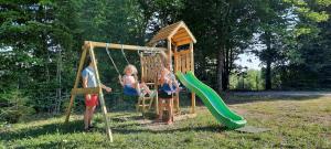 two children playing on a playground with a slide at Csendes Bükk 2 Kulcsosház in Izvoare