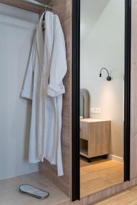 a mirror in a bathroom with a white robe hanging at BnB Hotel Shymkent in Shymkent