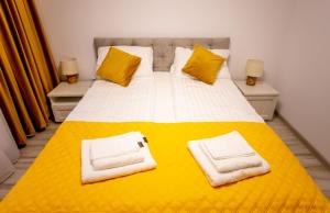 a bedroom with a yellow and white bed with towels on it at Loghin Residence in Suceava