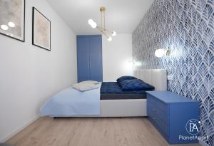 a bedroom with a blue bed and a wall at PlanetAparts in Darłowo