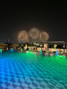 una piscina por la noche con fuegos artificiales en el fondo en mass paradise2, en Áqaba