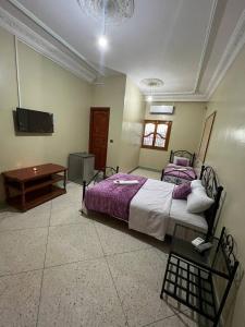 a bedroom with two beds and a table and a tv at Riad Perlamazigh in Zagora